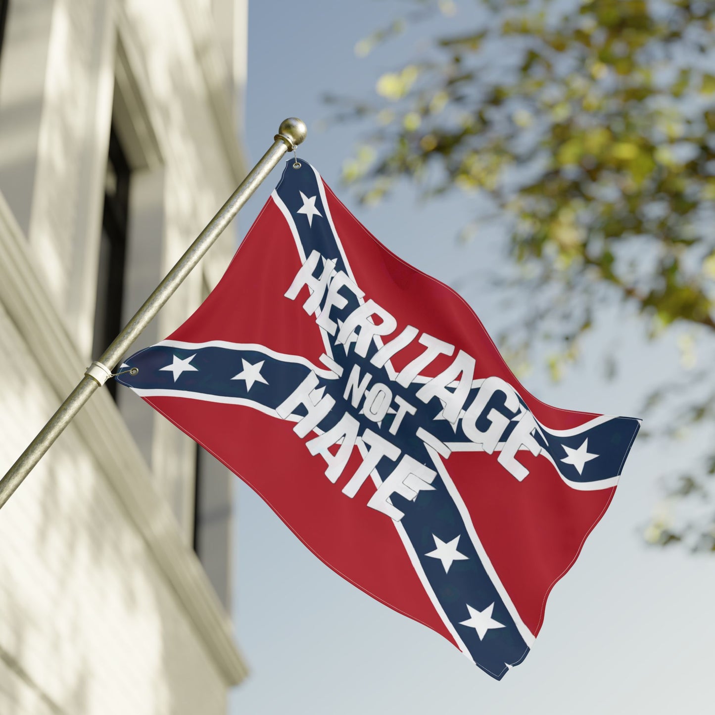 Heritage not hate flag waving outdoors attached to a metal flagpole in front of a building