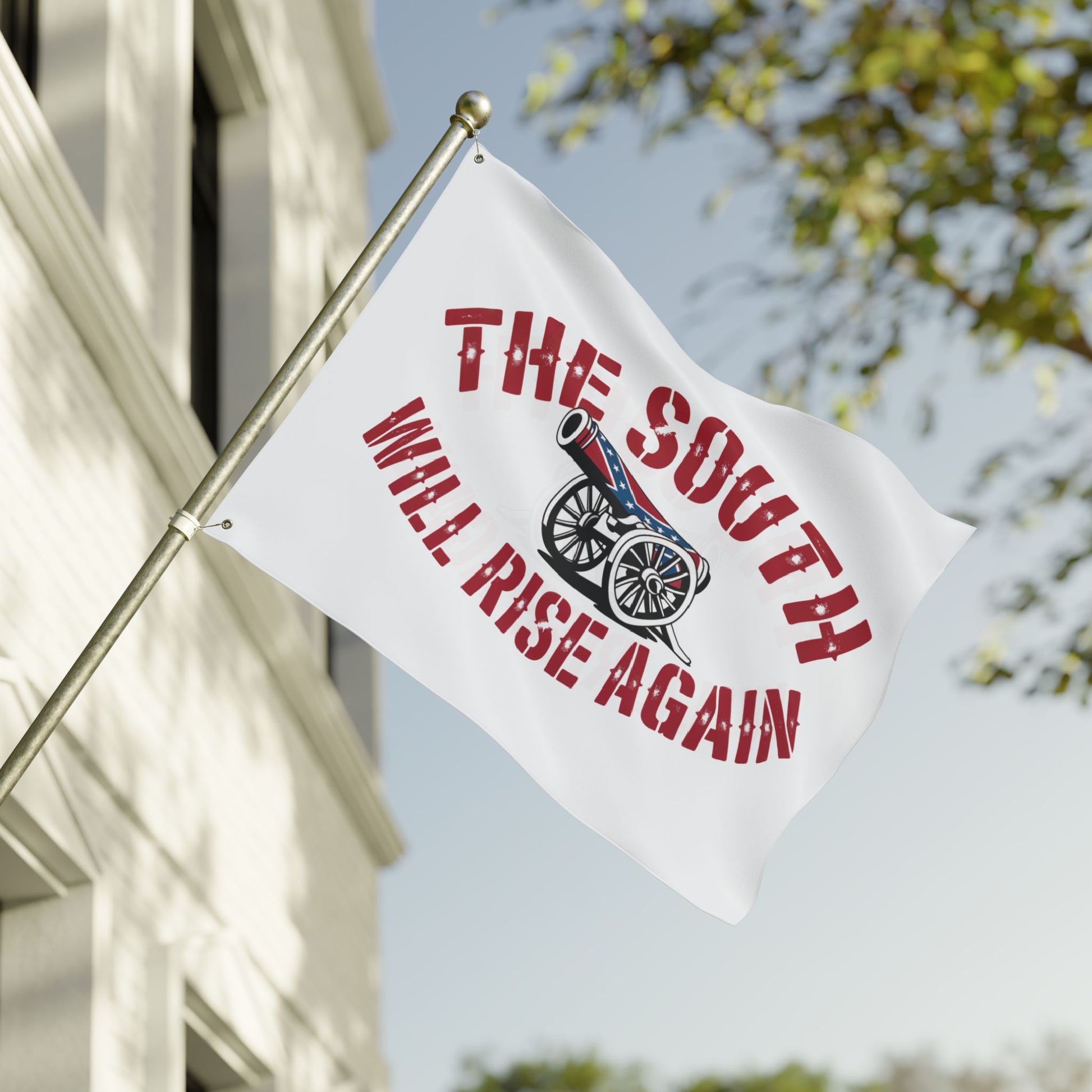 White flag with cannon and red text The South Will Rise Again Confederate flag waving on a pole outside a house